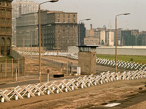 The Berlin Wall death strip with a guard tower and rows of anti-vehicle barriers