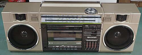 A silver Sharp GF-7600 boombox with dual speakers and a cassette deck, viewed at an angle