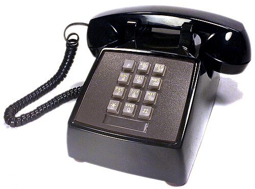 A classic black AT&T Western Electric push-button desk telephone with a coiled cord