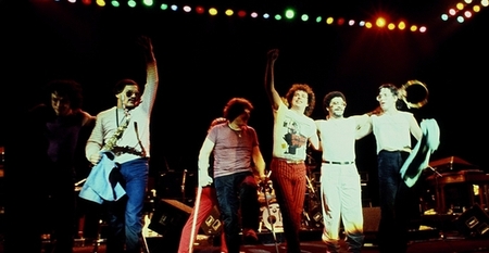 Toto performing on stage in 1982, band members raising their arms together at the end of a song