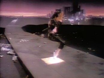 A still from the Billie Jean music video showing Michael Jackson dancing on a lit sidewalk panel at night