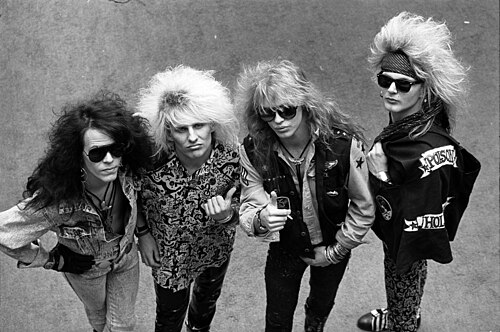 A black and white photo of the four members of Poison standing together, 1987