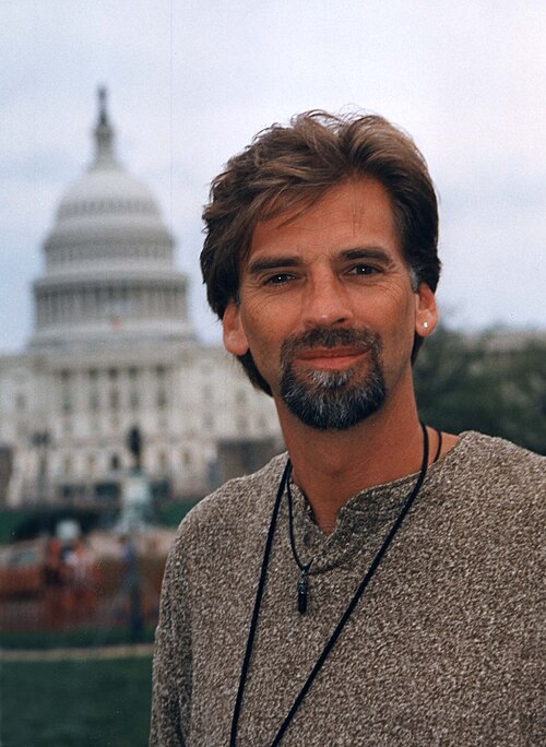 A portrait of Kenny Loggins with the U.S. Capitol building visible in the background