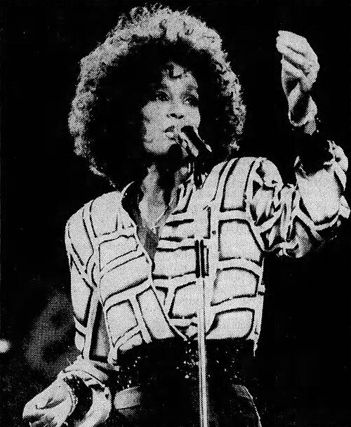 Whitney Houston singing into a microphone on stage, 1987
