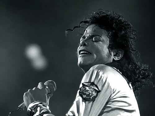 Michael Jackson singing into a microphone on stage in 1988, head tilted back with his eyes shut