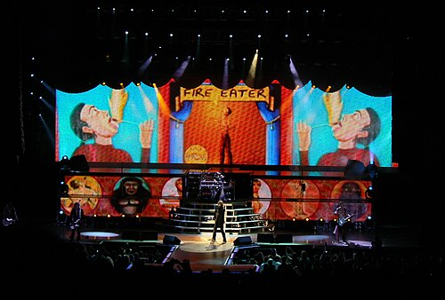 Def Leppard performing on a large concert stage with colorful backdrop screens