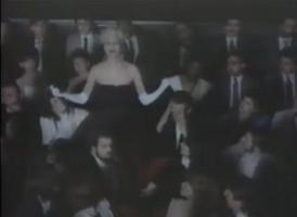 Aimee Mann standing up in the Carnegie Hall audience scene from the Voices Carry music video
