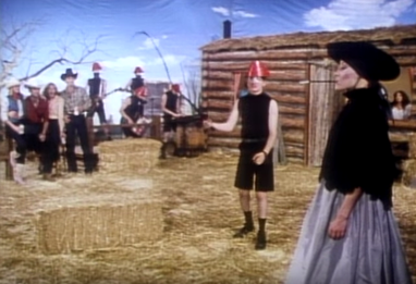 A still from the Whip It music video showing a dude ranch scene with cowboy hats and hay bales