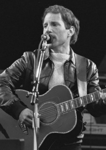 Paul Simon singing and playing guitar on stage in 1982